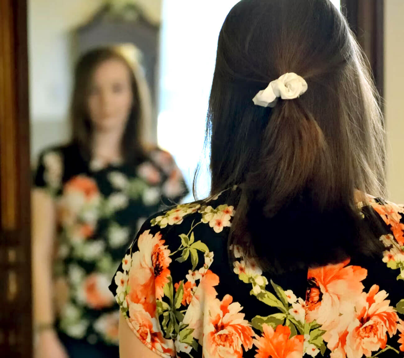 Photo of woman looking into mirror. 