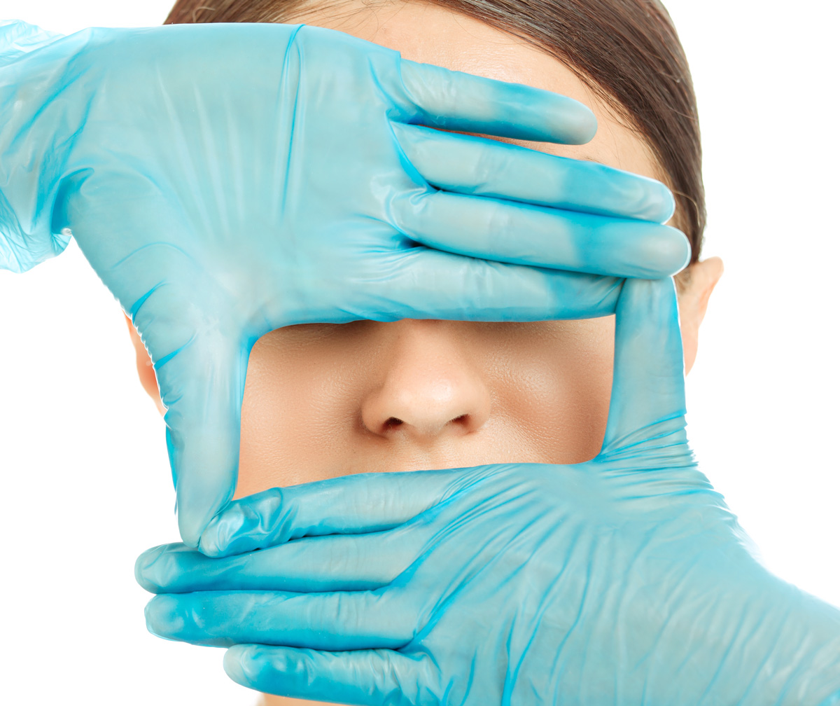 Photo of surgeon framing patient nose with hands.