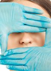 Photo of surgeon framing patient nose with hands.
